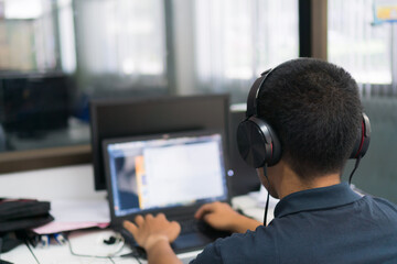 Student Asian man programmer with headphones learning online watching webinar training technology...