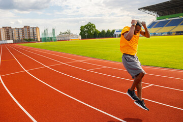 Fototapeta premium Joyful Afro American runner in yellow sportswear happily jumping and winning the runner competition, receiving first place, training and working hard to win the race. Victory concept