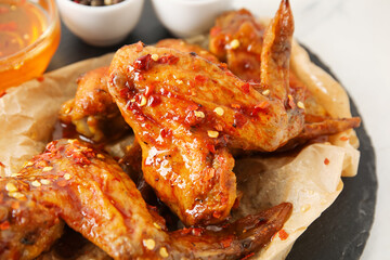 Tasty fried chicken wings and hot honey on table, closeup