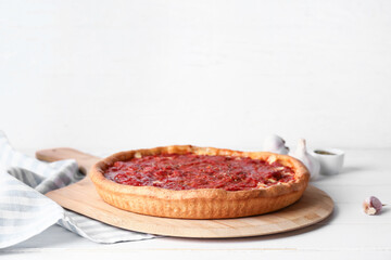 Board with tasty Chicago-style pizza on light background