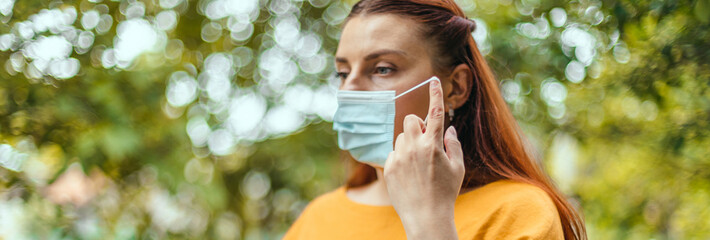 Happy woman takes off her protective medical mask from her face to breathe fresh air after the end...