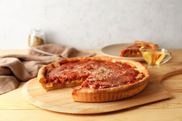 Board with tasty Chicago-style pizza on wooden table