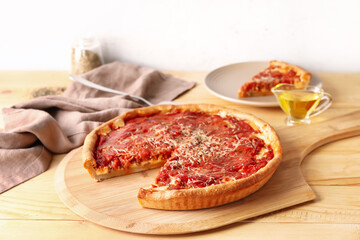 Board with tasty Chicago-style pizza on wooden table