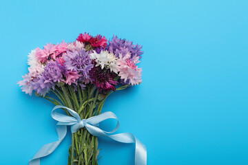 Bouquet of beautiful cornflowers on light blue background, top view. Space for text