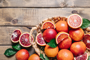 Composition of pile of blood oranges in a basket on a wooden table background. Flat lay, top view,...