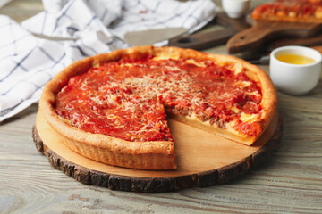Tasty Chicago-style pizza and oil on wooden background