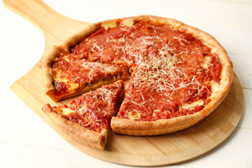 Board with tasty Chicago-style pizza on light wooden background