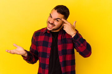 Young caucasian man isolated on yellow background showing a disappointment gesture with forefinger.