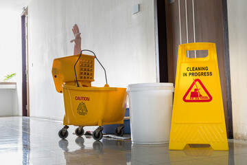 Close up yellow warning sign with message Cleaning in progress with cleaning trolley background