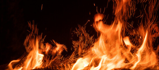 Beautiful flame of bonfire with sparks with dark night sky background. Fire tonques isolated on...