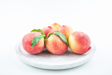 Fresh peaches in a pot on white background