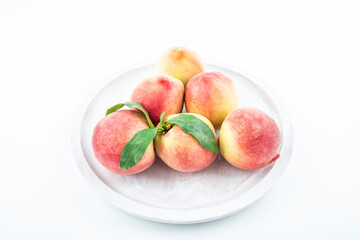 Fresh peaches in a pot on white background