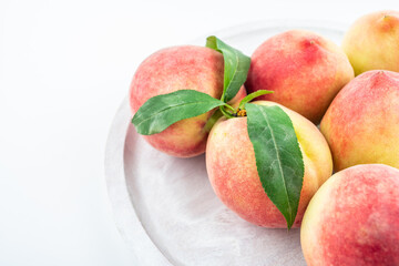 Fresh peaches in a pot on white background
