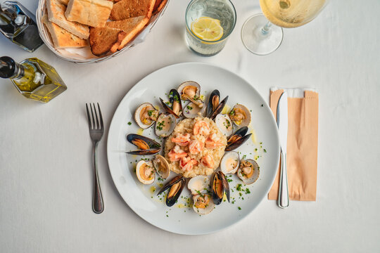 risotto with shrimps, mussels, served with a glass of white wine and a basket of bread
