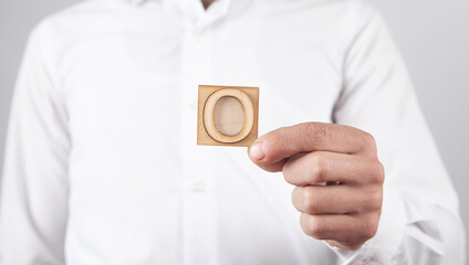 Man holding wooden number 0 symbol.