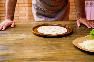 man in apron. flatbread pita on a round wooden cutting board. bakery. flat bread