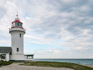Fototapeta na wymiar Lighthouse tower on a beach. The Lighthouse - Sletterhage fyr was built in 1894 and is still working in Denmark today