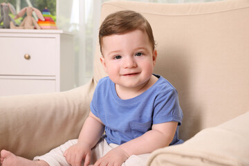 Fototapeta premium Happy baby boy sitting in armchair at home