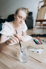 A young female artist in the process of working in a modern interior.The student draws a sketch for an architectural project, uses a liner and watercolors.The lifestyle of a modern creative person