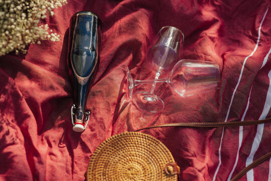 Top View Of Two Glasses And Bottle Of Red Wine On The Red Blanket At Picnic. 