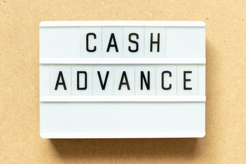 Lightbox with word cash advance on wood background