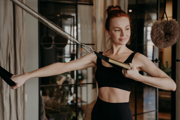 Training time of healthy happy ginger woman, exercising on cadillac reformer