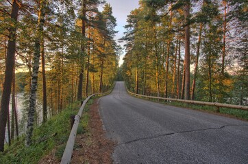 Summer road between lakes at sunset