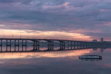 Obraz premium Bridge over the water during beautiful sunset and sunrise sun. Sunset over the bridge, purple blue yellow orange sky.