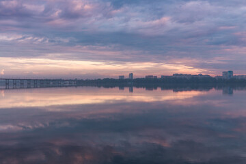 Obraz premium Beautiful sunset sky in the city. Sunrise or sunset. Dnepr River. The sky is reflected in a quiet river. Photo from Drona