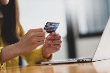 Young woman holding credit card in hand and laptop on the table, Online shopping.