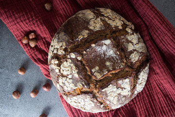 Beautiful and tasty rye bread on a table. Fresh homemade bread with oats and hazelnuts. Eating healthy concept. Artisan bread top view. Crusty loaf texture close up photo. 