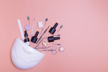 Manicure lamp and tools for applying varnish top view on a colored background. Salon manicure concept photo