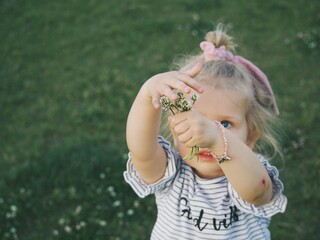 little girl picks flowers on a log in the park