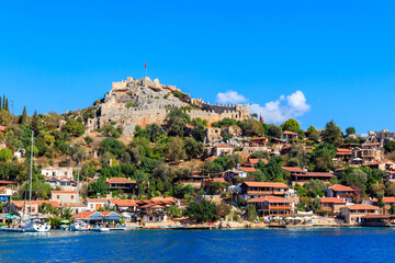 Fototapeta na wymiar View of ancient Lycian town Simena with fortress on a mount on the coast of the Mediterranean sea in Antalya Province, Turkey