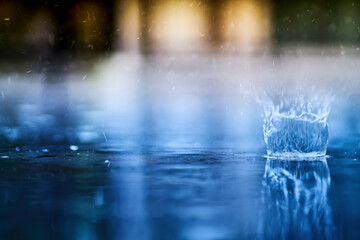 small splashing crown from rain's droplet when fall down on the floor in rainy day with blue shade color tone and golden sun light behind