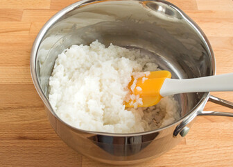 Scoop with rice porridge on wooden background