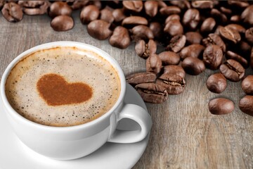 Cafes and restaurants. A mug of black coffee with foam in a heart shape and coffee beans.