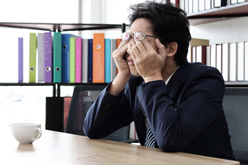 Unemployed stressed young Asian business man sitting in workplace. Failure and layoff concept.