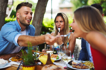 Happy friends having lunch in the restaurant during a sunny summer day
