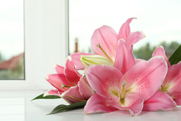 Beautiful pink lily flowers on window sill indoors