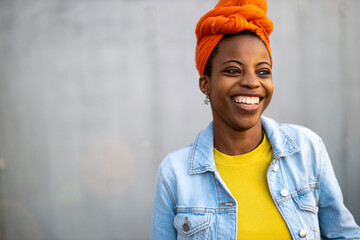 Beautiful young woman smiling in front of gray wall 
