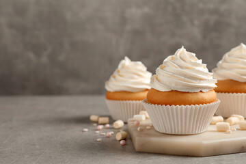 Delicious cupcakes decorated with cream on light grey table. Space for text