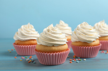 Delicious cupcakes decorated with cream on light blue wooden table