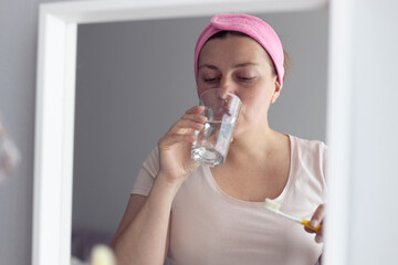 Young girl rinses her mouth and brushes her teeth in the bathroom. Hygiene, dental care concept.
