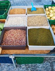 Different types of beans of various colors and lupins in bags for sale in bulk at a local flea market