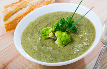 Healthy cream soup of broccoli served in white soup bowl with fresh bread ..