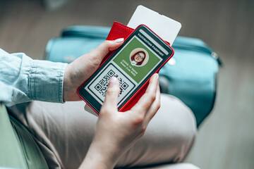 Woman traveler holding a passport, ticket pass and smartphone. Tourist using immunity passport app for travel during covid-19 pandemic.