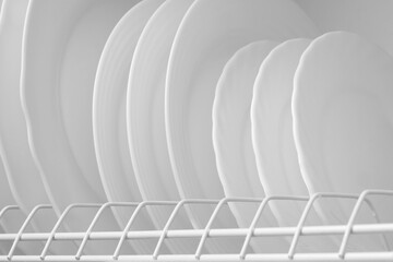 Clean white plates on dish drainer drying after washing