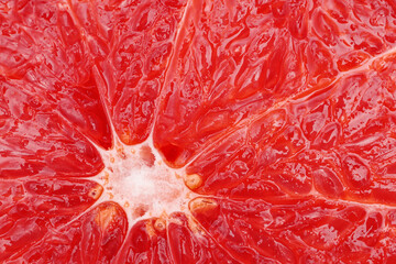 Macro of ripe grapefruit pulp. Slice of red grapefruit close up. Grapefruit fruit texture wallpaper background