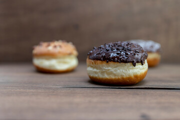 Delicious glazed chocolate donuts on wooden background